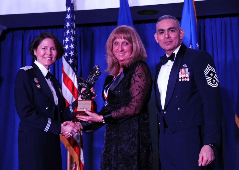 Diane Munson accepts the 2013 Air Force District of Washington Annual Awards Civilian Category III of the Year trophy from AFDW Commander Maj. Gen. Sharon K. G. Dunbar and AFDW Command Chief Master Sgt. Jose LugoSantiago during the awards ceremony at Joint Base Anacostia-Bolling, D.C., March 21, 2014. Munson works at the 11th Wing, 11th Operations Group. (U.S. Air Force photo/Master Sgt. Tammie Moore) 