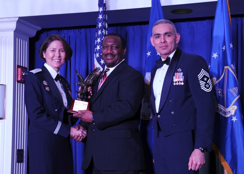 Robert Naylor accepts the 2013 Air Force District of Washington Annual Awards Civilian Category II of the Year trophy from AFDW Commander Maj. Gen. Sharon K. G. Dunbar and AFDW Command Chief Master Sgt. Jose LugoSantiago during the awards ceremony at Joint Base Anacostia-Bolling, D.C., March 21, 2014. Naylor works at the 11th Wing, 11th Security Support Squadron. (U.S. Air Force photo/Master Sgt. Tammie Moore) 