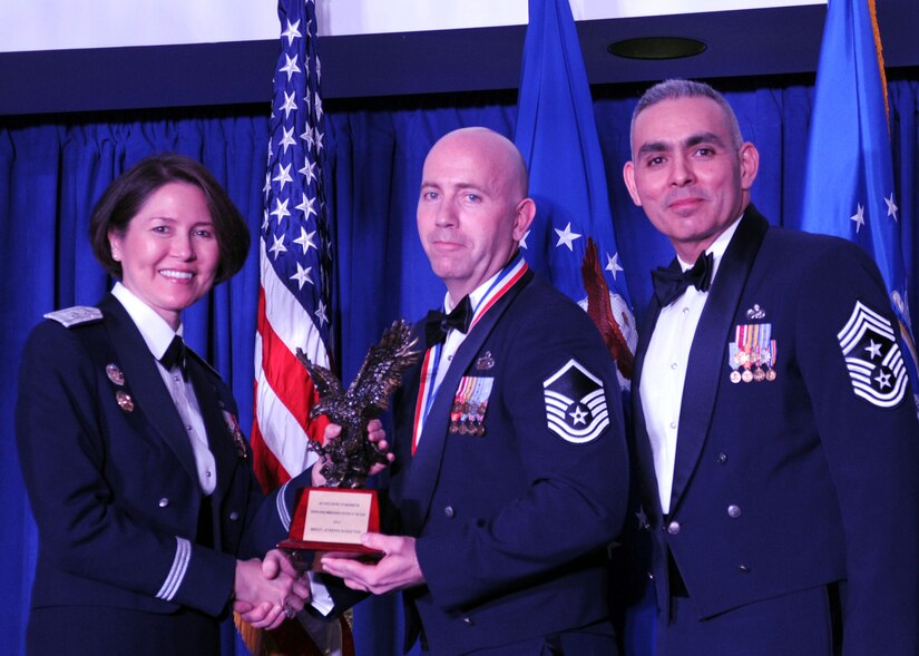 Master Sgt. Joseph Koester accepts the 2013 Air Force District of Washington Annual Awards SNCO of the Year trophy from AFDW Commander Maj. Gen. Sharon K. G. Dunbar and AFDW Command Chief Master Sgt. Jose LugoSantiago during the awards ceremony at Joint Base Anacostia-Bolling, D.C., March 21, 2014. Koeste is the 11th Wing, 11th Force Support Squadron Military Personnel Flight superintendent. (U.S. Air Force photo/Master Sgt. Tammie Moore) 