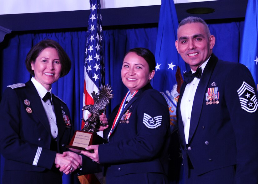 Tech. Sgt. Kimberly Weaver-Cruz accepts the 2013 Air Force District of Washington Annual Awards NCO of the Year trophy from AFDW Commander Maj. Gen. Sharon K. G. Dunbar and AFDW Command Chief Master Sgt. Jose LugoSantiago during the awards ceremony at Joint Base Anacostia-Bolling, D.C., March 21, 2014. Weaver-Cruz works at the 79th Medical Wing, 779th Dental Squadron. (U.S. Air Force photo/Master Sgt. Tammie Moore) 