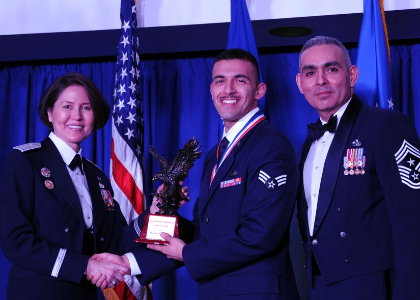 Senior Airman Peter Stambouli accepts the 2013 Air Force District of Washington Annual Awards Airman of the Year trophy from AFDW Commander Maj. Gen. Sharon K. G. Dunbar and AFDW Command Chief Master Sgt. Jose LugoSantiago during the awards ceremony at Joint Base Anacostia-Bolling, D.C., March 21, 2014. Stambouli is an 11th Wing, 11th Comptroller Squadron customer service technician. (U.S. Air Force photo/Master Sgt. Tammie Moore) 