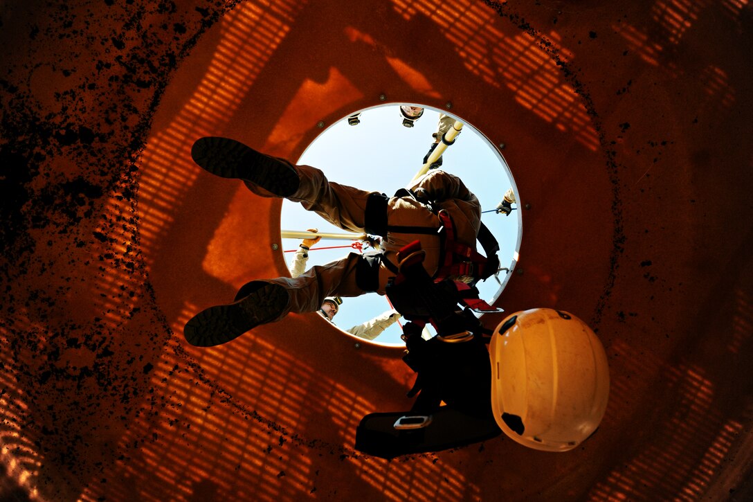 Airman 1st Class Tevin Charles, 11th Civil Engineer Squadron firefighter, lowers himself down into the Fire Training Area vertical confined space trainer during a rescue scenario on Joint Base Andrews, Md., March 20, 2014. (U.S. Air Force photo/Airman 1st Class Nesha Humes)