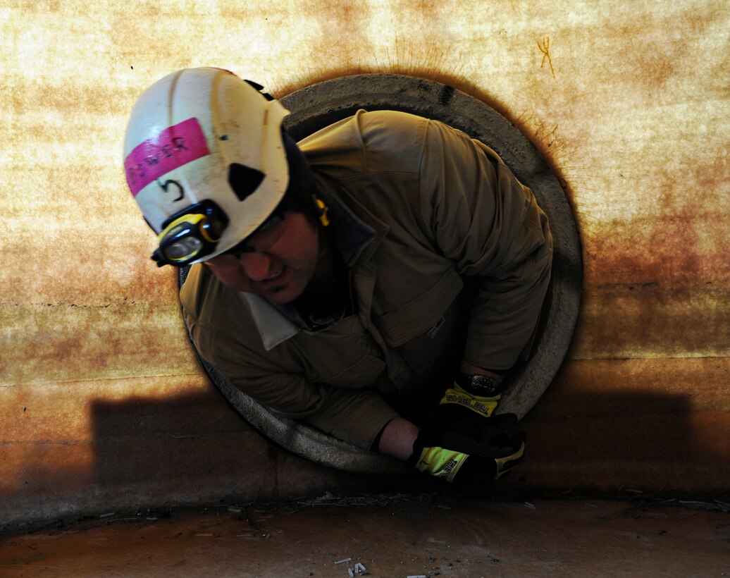 James Bower, Naval District of Washington firefighter, climbs out of a horizontal confined space at the Fire Training Area on Joint Base Andrews, Md., March 19, 2014. (U.S. Air Force photo/Airman 1st Class Nesha Humes)