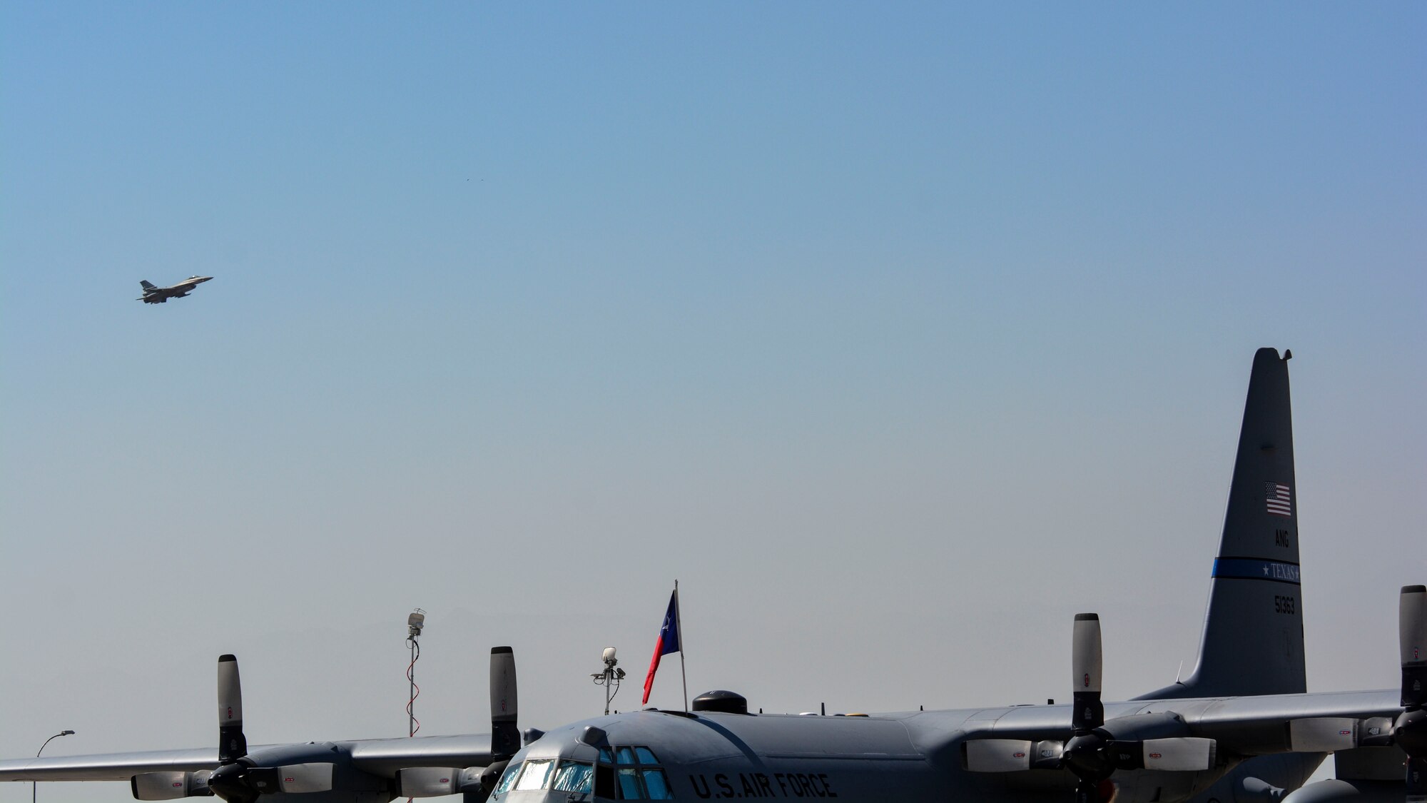 A U.S. Air Force C-130 Hercules, from the Texas Air National Guard, sits on the ramp during a Chilean air force F-16 aerial demonstration at the first day of the FIDAE Air Show in Santiago, Chile, March 25. Nearly 60 U.S. airmen are participating in subject matter expert exchanges with Chilean air force counterparts during FIDAE, and as part of the events will host static displays of the C-130 and F-16.  The exchanges, conducted regularly throughout the year, involve U.S. airmen sharing best practices and procedures to build partnerships and promote interoperability with partner-nations throughout South America, Central America and the Caribbean. (U.S. Air Force photo by Capt. Justin Brockhoff/Released)