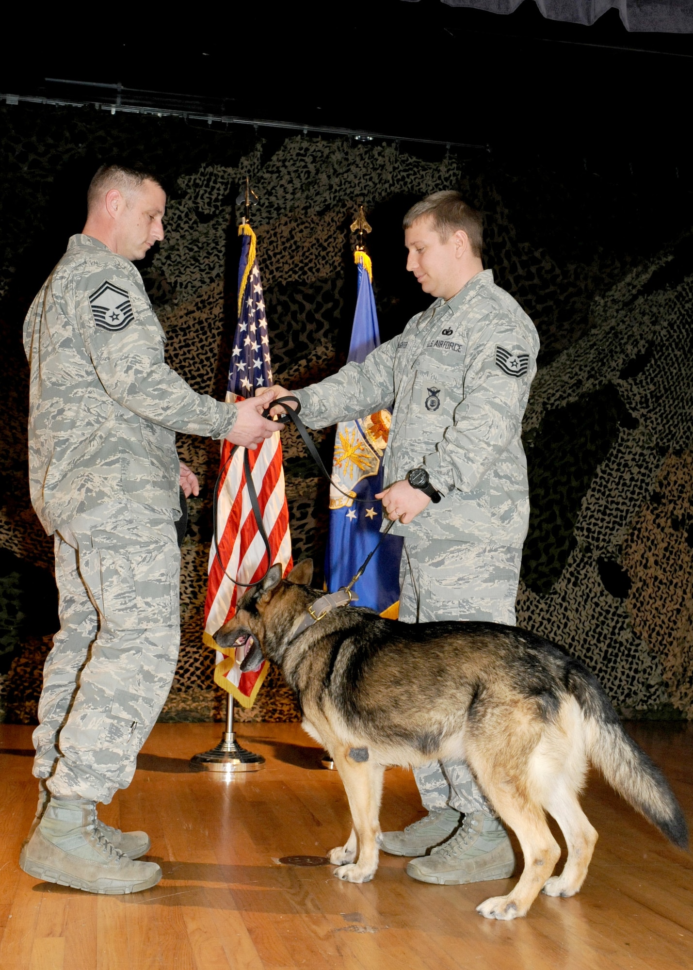 Tech. Sgt. Edward Slaughter (right), 65th SFS kennel master, hands over Military Working Dog Dan to his new partner upon retirement, Senior Master Sgt. Jason Tranfaglia (left), 65th SFS manager. The 65th SFS hosted a retirement ceremony for MWD Dan, a nine-year U.S. Air Force veteran, March 25, 2014. Dan served as a devoted team member to 10 MWD handlers as a narcotics detector on Lajes Field, Azores. He is now adopted by Tranfaglia. (U.S. Air Force photo by Guido Melo/Released) 
