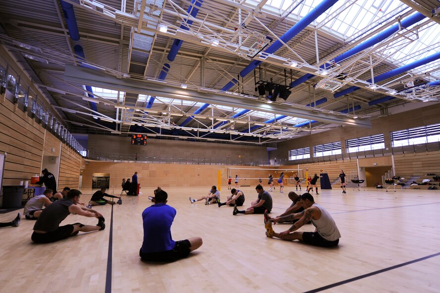 The U.S. Air Forces in Europe and Air Forces Africa women's volleyball team warm-up as the men's team stretches during the final day of their training camp March 24, 2014, at Spangdahlem Air Base, Germany. The women’s team is currently undefeated in the Headquarters Allied Air Command Inter-Nation Sports Programme Volleyball Championships. (U.S. Air Force photo by Senior Airman Rusty Frank/Released)
