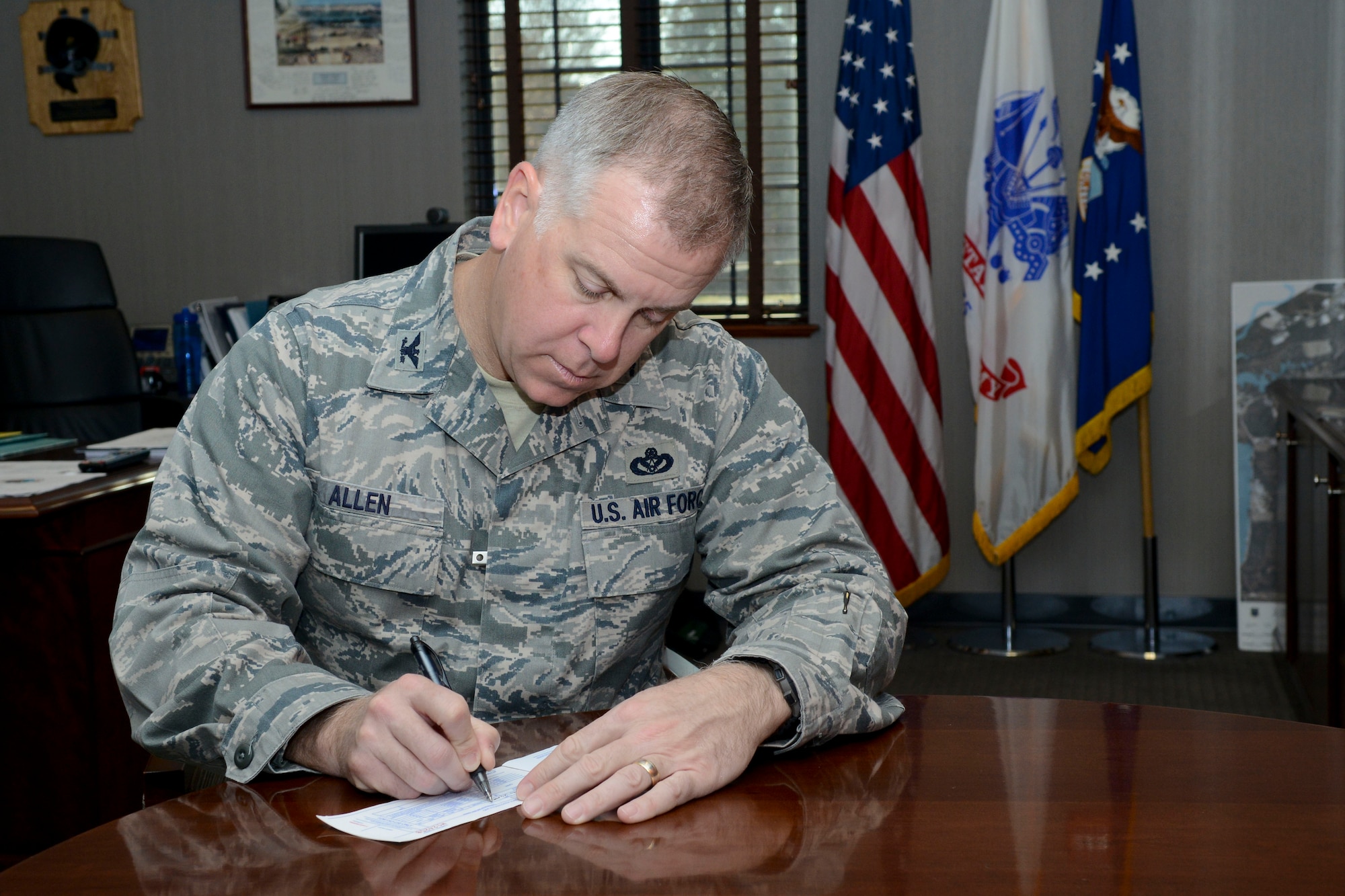 U.S. Air Force Col. John J. Allen Jr., 633rd Air Base Wing commander, signs an Air Force Assistance Fund donation form at Langley Air Force Base, Va., March 26, 2014. The AFAF is an annual campaign that raises money on active duty military installations to benefit four different charitable organizations that support Air Force families in need. This year’s campaign will run from March 24 to May 2. (U.S. Air Force photo by Airman 1st Class Victoria H. Taylor/Released)