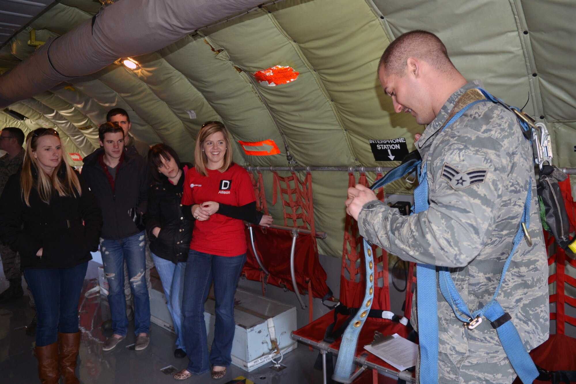 U.S. Air Force Senior Airman Jarred McGlothlin, 100th Aircraft Maintenance Squadron aircraft instruments and flight control systems journeyman from Elkton, Md., demonstrates to spouses how to put on a harness March 21, 2014, on RAF Mildenhall, England. The Airmen’s Council led a flightline tour and an isochronal inspection dock hangar tour for the spouses visit. (U.S. Air Force photo by Airman 1st Class Kyla Gifford/Released) 