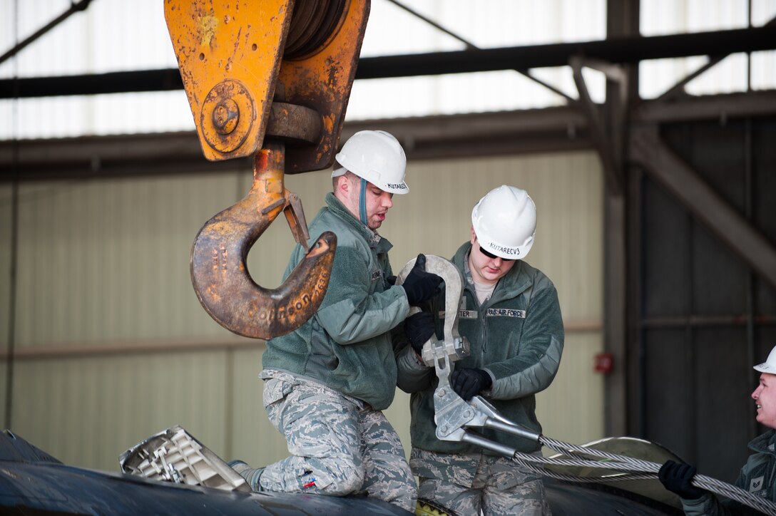 Staff Sgt. Michael Darlymple and Senior Airman Alex Feaster, 8th Maintenance Squadron crash damage disable aircraft team members, attach a damaged F-16 to a crane at Kunsan Air Base, Republic of Korea, Mar. 22, 2014. The crash recovery team chiefs were recertified and trained on damaged aircraft equipment for disposal. (U.S. Air Force photo by Staff Sgt. Clayton Lenhardt/Released)