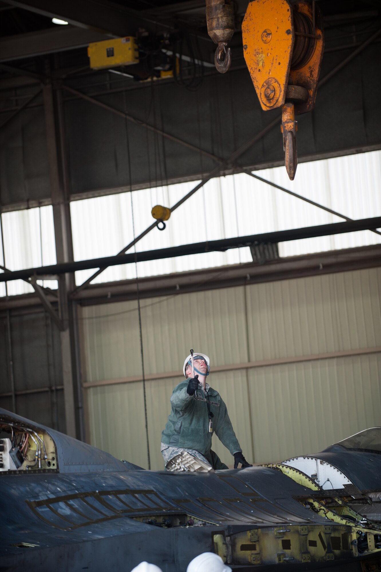 Staff Sgt. Michael Darlymple, 8th Maintenance Squadron crash damage disable aircraft team member, guides a crane hook to a damaged F-16 at Kunsan Air Base, Republic of Korea, Mar. 22, 2014. The crash recovery team chiefs were recertified and trained on damaged aircraft equipment for disposal. (U.S. Air Force photo by Staff Sgt. Clayton Lenhardt/Released)