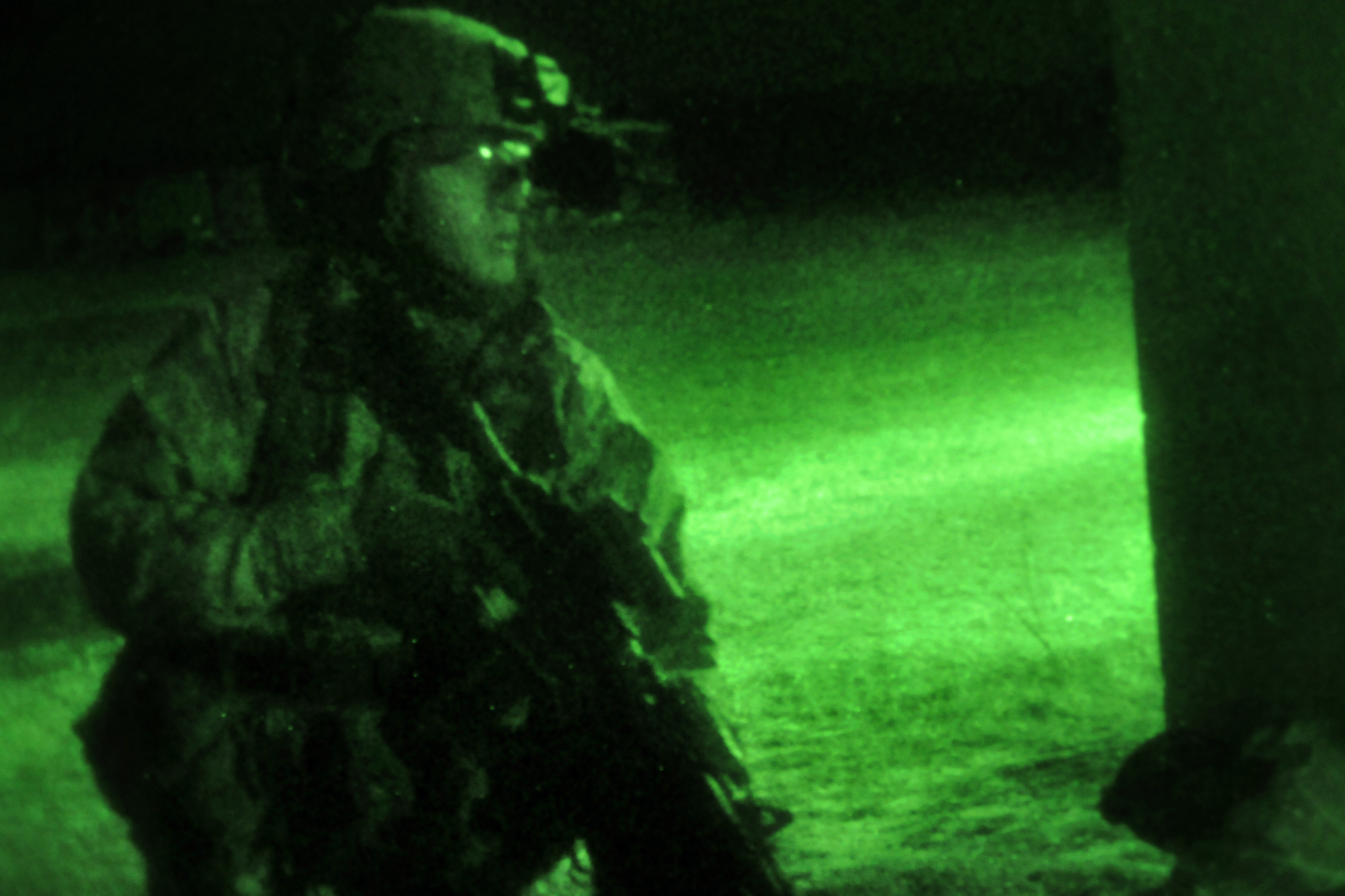 As seen through a nightvision device, a paratrooper moves around the