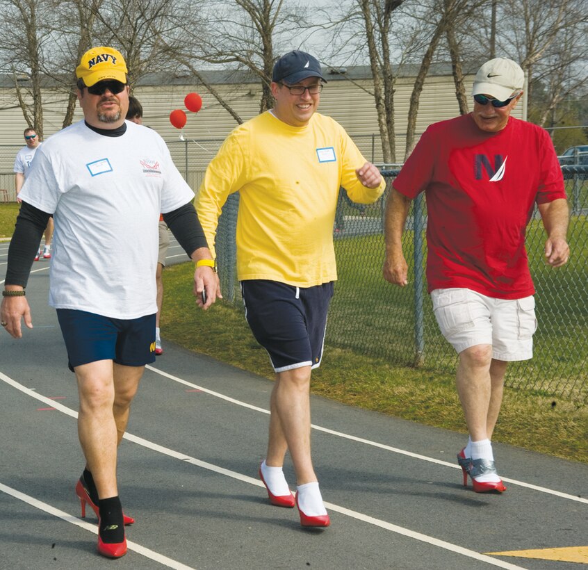 In step are Charles Goodson (left), Craig Pruett (center), and George Mettrick, all with Marine Corps Community Services, Marine Corps Logistics Base Albany. They were among more than 60 men who participated in the 4th annual Walk a Mile in Her Shoes charity event Saturday at Deerfield-Windsor School Upper Campus track in Albany, Ga. The event raised awareness for victims of sexual assault and abuse. 