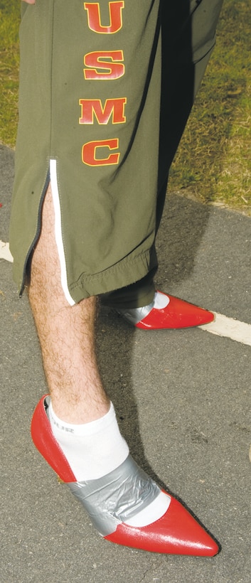 A Marine shows off his legs and bright red shoes duct taped to his feet during the 4th annual Walk a Mile in Her Shoes charity event Saturday at Deerfield-Windsor School Upper Campus track in Albany, Ga.