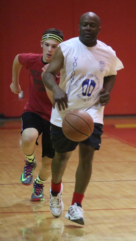 A Lejeune High School staff member races for the ball during the Lejeune March Madness basketball competition at Lejeune High School, March 21. The staff team won 73-60.