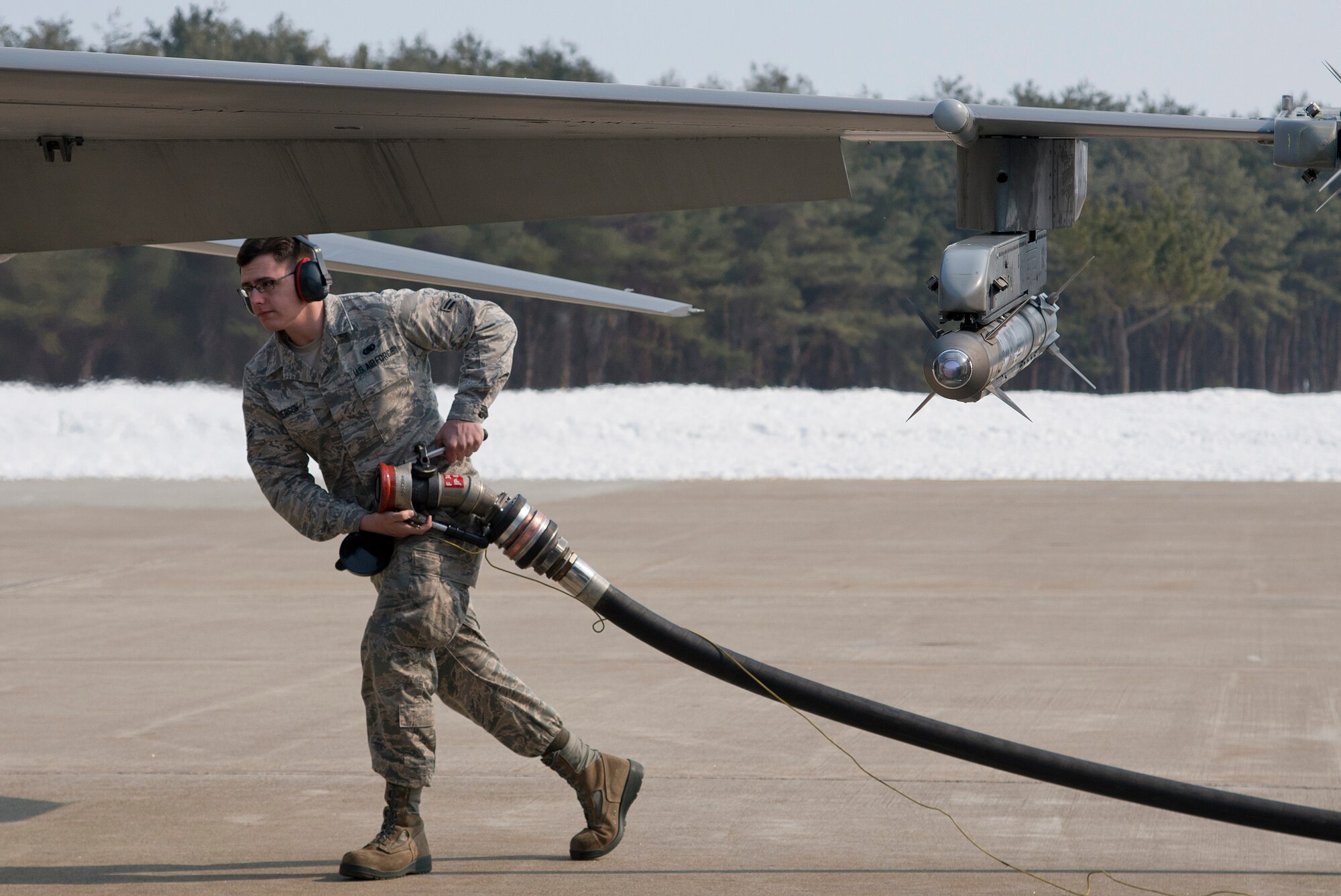 U.S. Air Force Airman 1st Class Sabastian Anderson, 35th Logistics Readiness Squadron fuels distribution operator, carries a gasoline hose to an F-16 Fighting Falcon at Misawa Air Base, Japan, March 25, 2014. Anderson is part of an 72-member flight that fuels over 40 jets split between two fighter squadrons. (U.S. Air Force photo/Airman 1st Class Patrick S. Ciccarone)