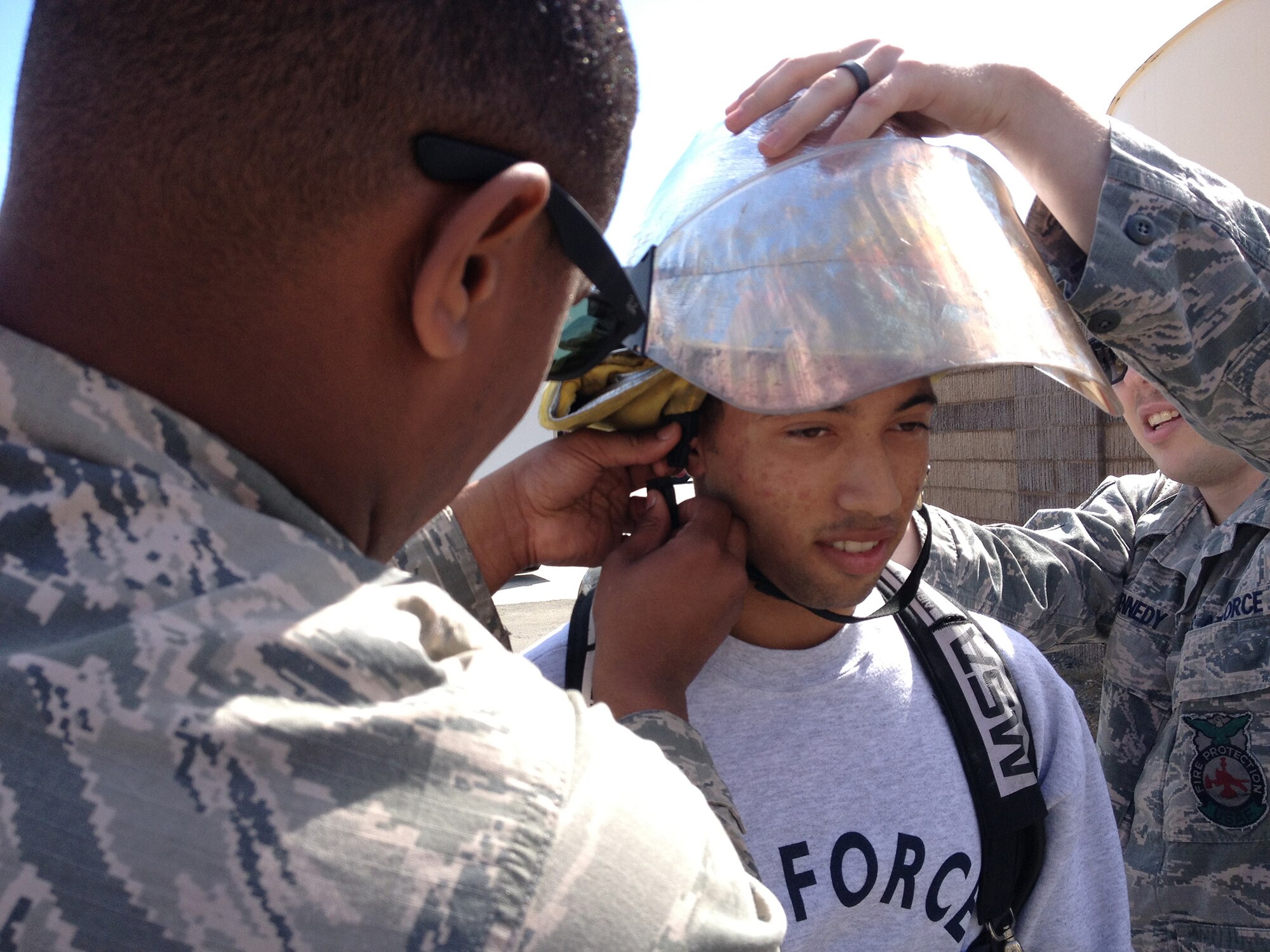 TRAVIS AIR FORCE BASE, Calif. -- A Junior ROTC student from River City High School, outside Sacramento, experiences the life of Air Force firefighters March 21, 2014, during a tour of Travis Air Force Base, Calif. With the help of Senior Airmen Caylon Moore (left) and Joshua Kennedy, students were shown the tools of the firefighter trade, providing them an up-close look at this Air Force career field. Moore and Kennedy are driver operators assigned to the 60th Civil Engineer Squadron. (U.S. Air Force photo/Tech. Sgt. Stephen J. Collier)