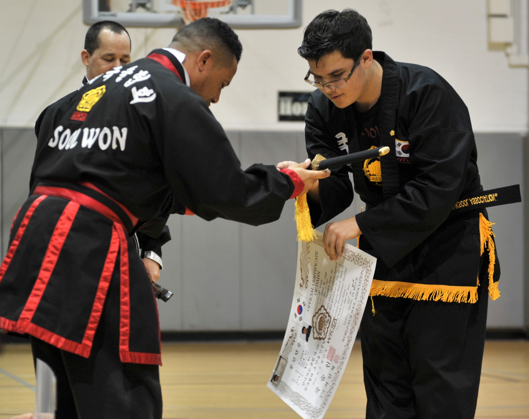 Retired Master Sgt. Amado Garcia, previously assigned to the 96th Aircraft Maintenance Squadron, Eglin Air Force Base, Fla., presents a sword and black belt certificate to Jakob Onge during the Kuk Sool Won Black Belt Demo at the Aderholt Fitness Center on Hurlburt Field, Fla, March 22, 2014. Garcia taught and promoted more than 50 black belts since he began instructing. (U.S. Air Force photo/Senior Airman Kentavist P. Brackin) 