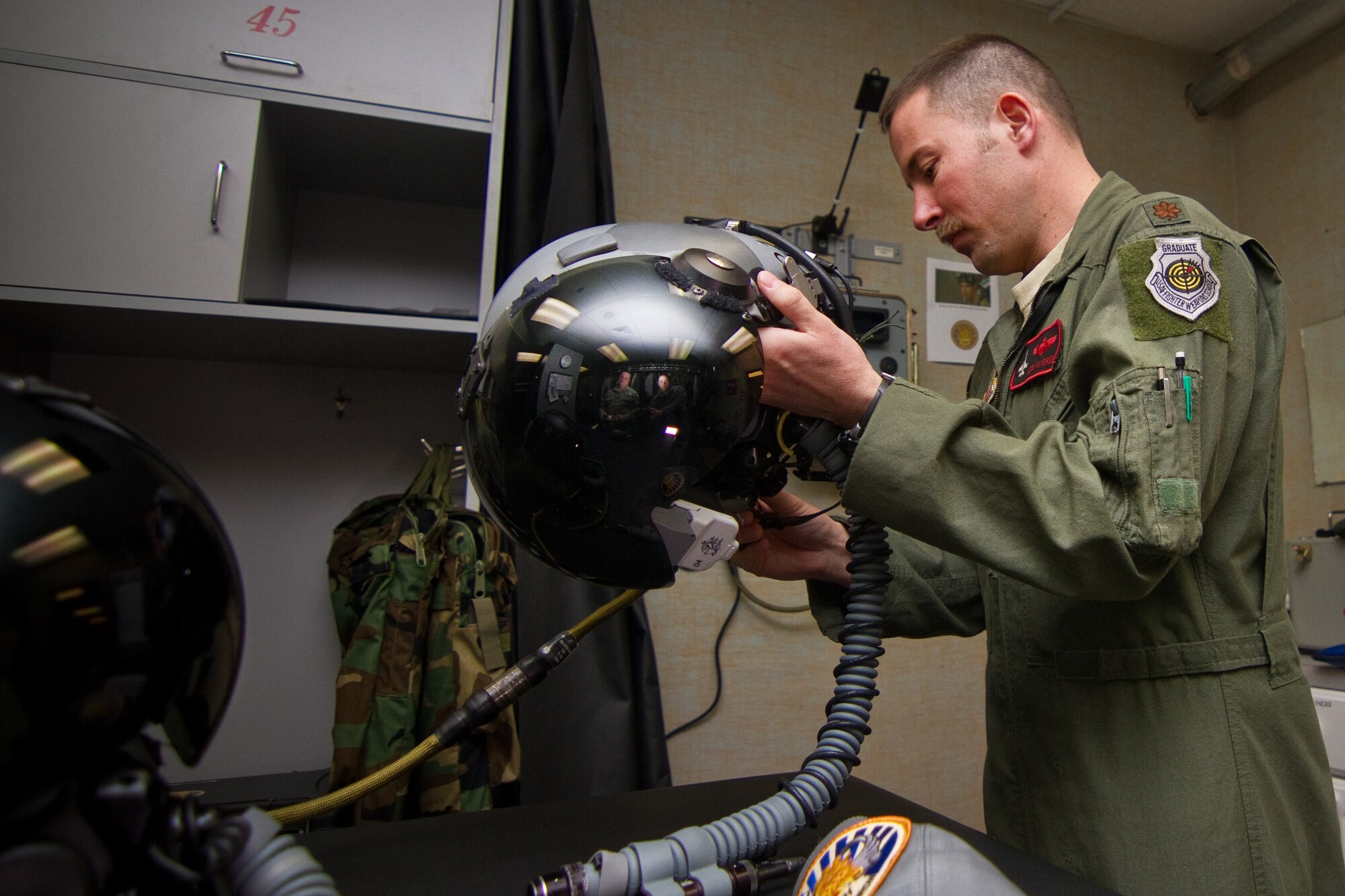 A picture of U.S. Air Force Maj. Jason Halvorsen inspecting his helmet with the Helmet Mounted Integrated Targeting system installed.