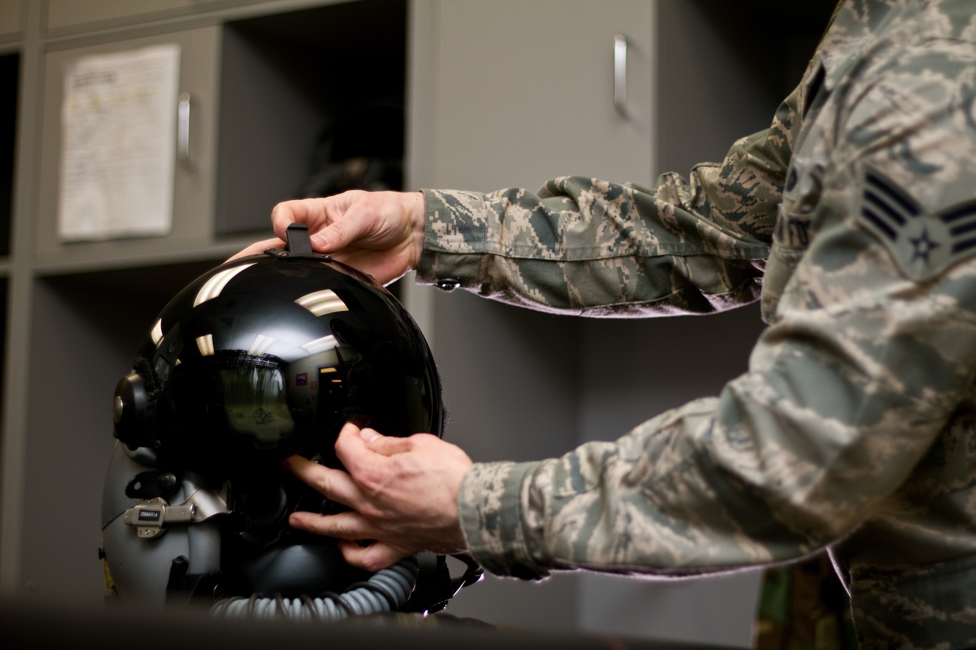 A picture of U.S. Air Force Senior Airman Eric Halladay inspecting an F-16 Fighting Falcon pilot's helmet with the Helmet Mounted Integrated Targeting (HMIT) system.