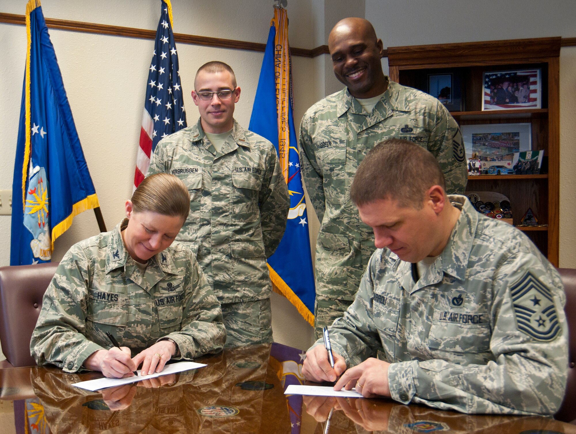Col. Tracey Hayes, 90th Missile Wing commander, and Chief Master Sgt. Michael Garrou, 90th MW command chief, fill out Air Force Assistance Fund donation forms in Hayes’ office March 24, 2014, while AFAF project officers, 2nd Lt. Mark Verbruggen and Master Sgt. Bertram Green, stand by. This kicked off AFAF fundraising efforts for the 90th Missile Wing. (Air Force photo by Airman 1st Class Jason Wiese)