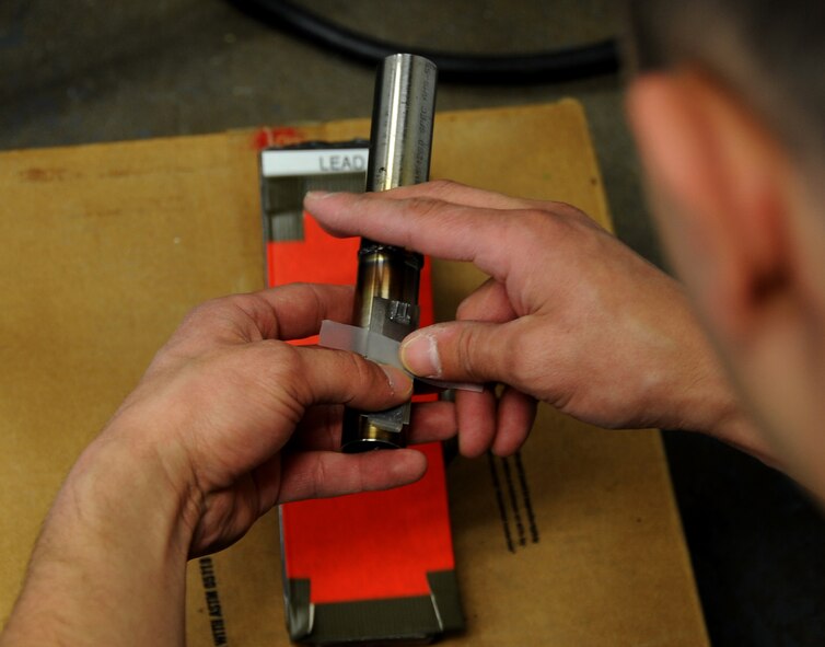 Staff Sgt. Josh Martinez, 2nd Maintenance Squadron, non-destructive inspection NCO in-charge, tapes an identification tag onto an aluminum tube being tested for cracks on Barksdale Air Force Base, La., March. 25, 2014. NDI Airmen inspect for cracks within the weld, proper penetration into the weld and porosity, which is gas formations that did not escape prior to the weld. (U.S. Air Force photo/Staff Sgt. Jason McCasland)