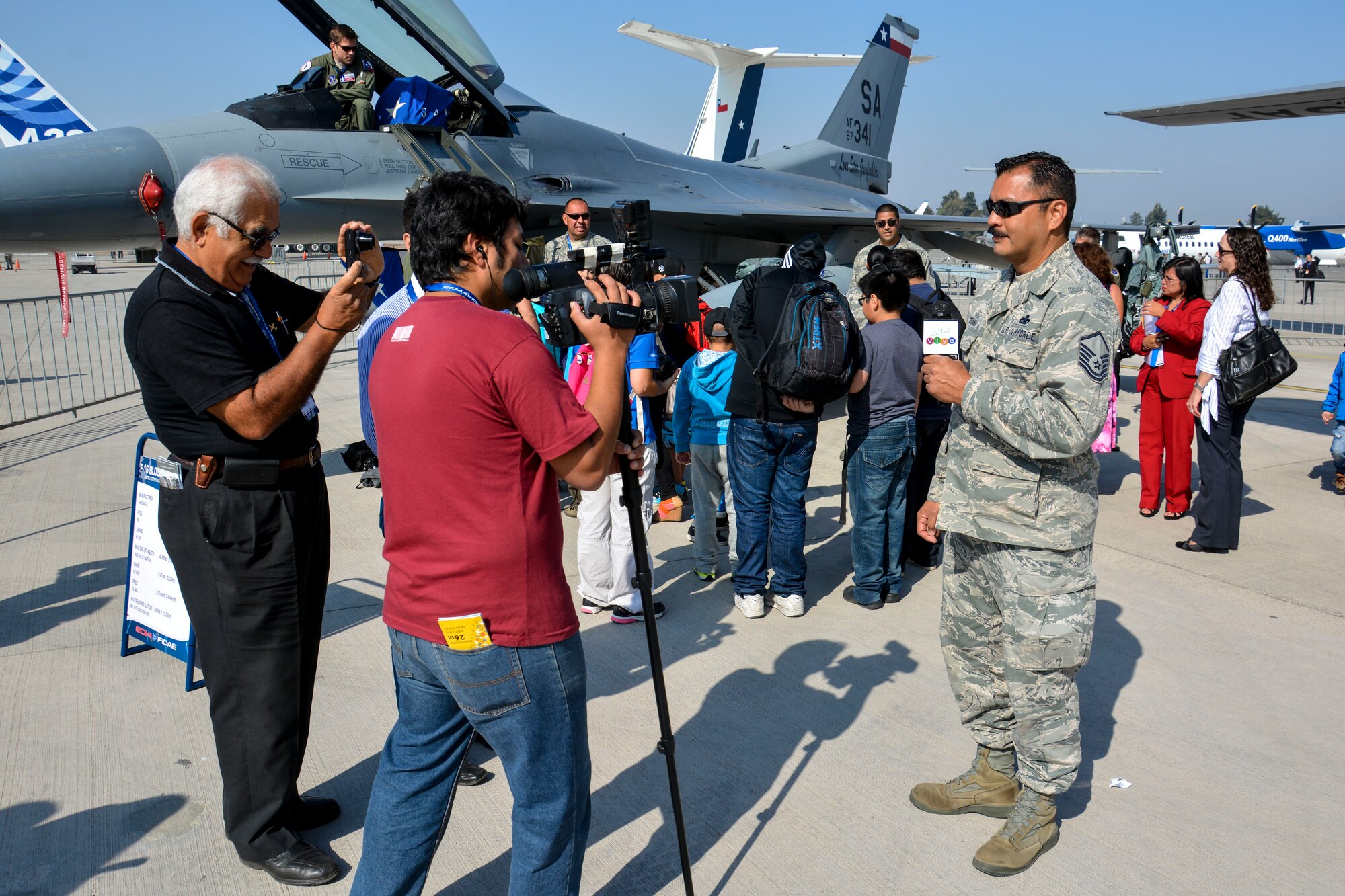 Master Sgt. Pablo Soriano, an aircraft maintenance specialist from the Texas Air National Guard, speaks with the media while children from the Make-A-Wish and Telet?n Foundations tour U.S. aircraft at the FIDAE Air Show in Santiago, Chile, March 26. Nearly 60 U.S. airmen are participating in subject matter expert exchanges with Chilean air force counterparts during FIDAE, and as part of the events are hosting static displays of the C-130 Hercules and F-16 Fighting Falcon. Airmen from the Texas Air National Guard set aside time to host the children before the public days of FIDAE, which are scheduled for the weekend. (U.S. Air Force photo by Capt. Justin Brockhoff/Released)