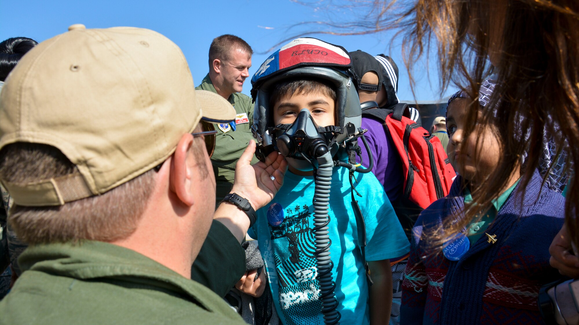 Lt. Col. Greg Pohoski (far left), a fighter pilot assigned to the Texas Air National Guard, helps a Chilean boy from the Make-A-Wish Foundation try on a helmet and oxygen mask at the FIDAE Air Show in Santiago, Chile, March 26. Nearly 60 U.S. airmen are participating in subject matter expert exchanges with Chilean air force counterparts during FIDAE, and as part of the events are hosting static displays of the C-130 Hercules and F-16 Fighting Falcon. Airmen from the Texas Air National Guard set aside time to host the children before the public days of FIDAE, which are scheduled for the weekend. (U.S. Air Force photo by Capt. Justin Brockhoff/Released)