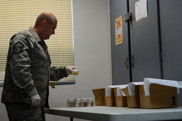 U.S. Air Force Master Sgt. Michael Eads, 20th Medical Group Drug Demand Reduction program administrative manager, checks for accuracy on a urine sample label before shipment, Shaw Air Force Base, S.C., March 25, 2014. After packing each eight-container box, the boxes are packed into a larger box before being shipped to Lackland AFB, Texas, for testing. (U.S. Air Force photo by Airman 1st Class Jensen Stidham/Released) 
