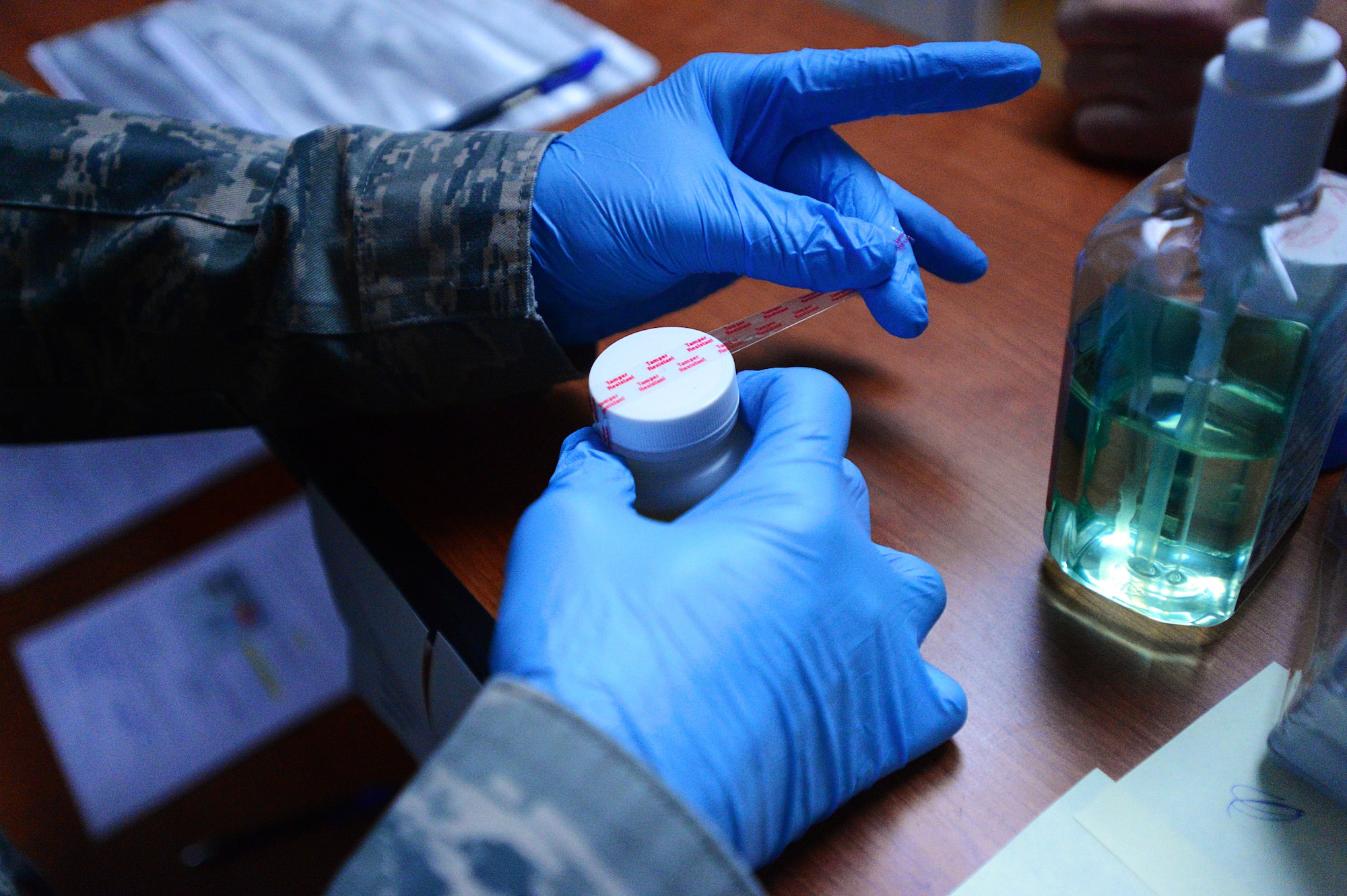 A 20th Medical Group Drug Demand Reduction program administrative manager seals a specimen container with tamper proof tape at the DDR facility, Shaw Air Force Base, S.C., March 25, 2014. The tamper tape is used to ensure that the lid stays securely on the container and that an individual has not tried to contaminate it. (U.S. Air Force photo by Airman 1st Class Jensen Stidham/Released)