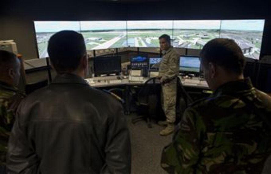 U.S. Air Force Tech. Sgt. Briant Bell, 52nd Operations Support Squadron air traffic controller, demonstrates the air traffic control simulator for members of the Romanian air force during a familiarization tour at Spangdahlem Air Base, Germany, March 26, 2014. The tour was the first in a series of engagements designed to expose Romanian air force officials to the operations, maintenance and support required to operate an F-16 Fighting Falcon fighter aircraft squadron. (U.S. Air Force photo by Staff Sgt. Chad Warren/Released)