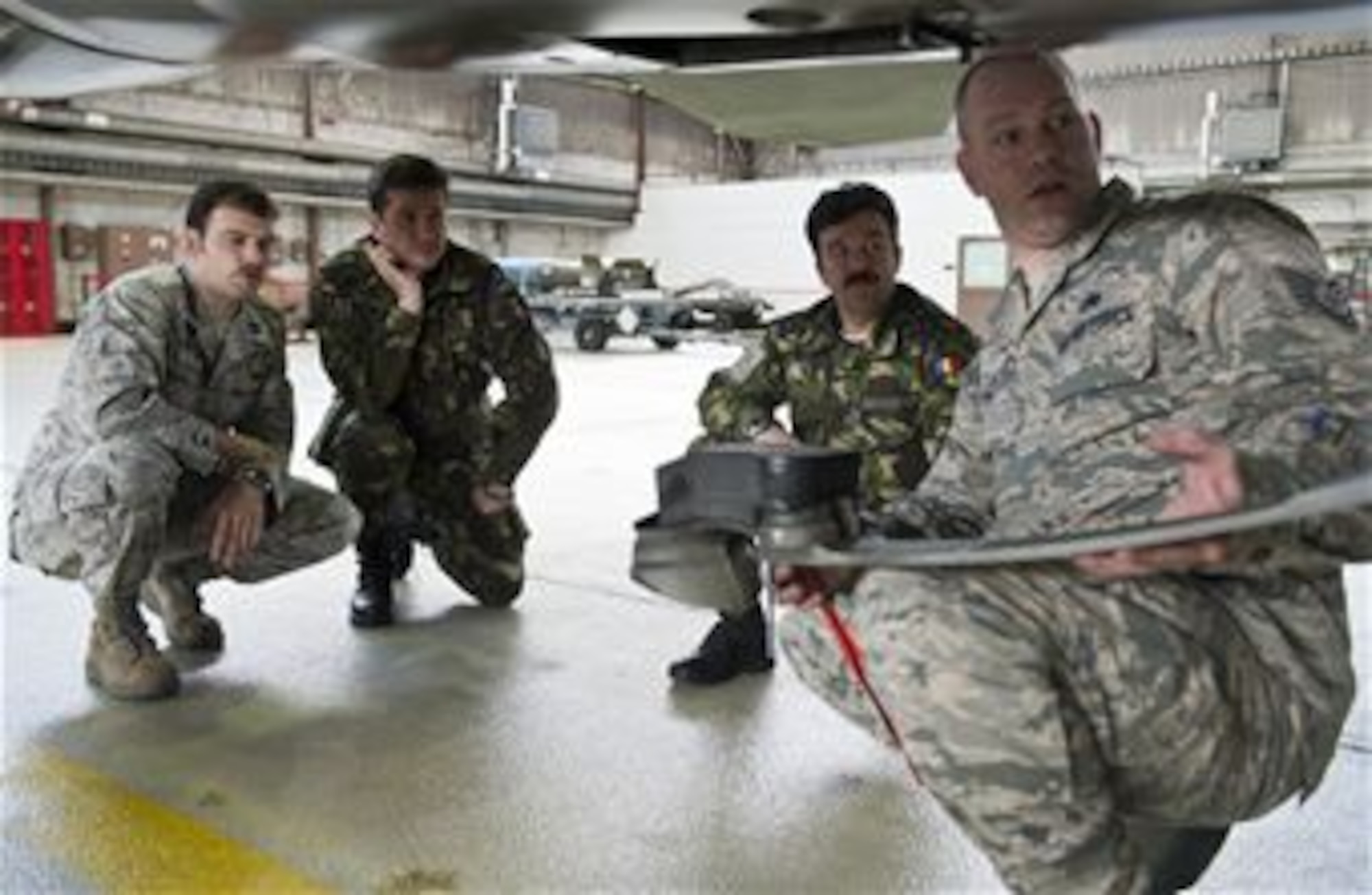U.S. Air Force Tech. Sgt. John Lyon, 52nd Aircraft Maintenance Squadron crew chief, explains F-16 Fighting Falcon fighter aircraft capabilities to members of the Romanian air force during a familiarization tour at Spangdahlem Air Base, Germany, March 25, 2014. The Romanian air force, who recently entered a contract to purchase 12 F-16s, visited Spangdahlem to gain insight into F-16 operations, maintenance and support. (U.S. Air Force photo by Staff Sgt. Chad Warren/Released)