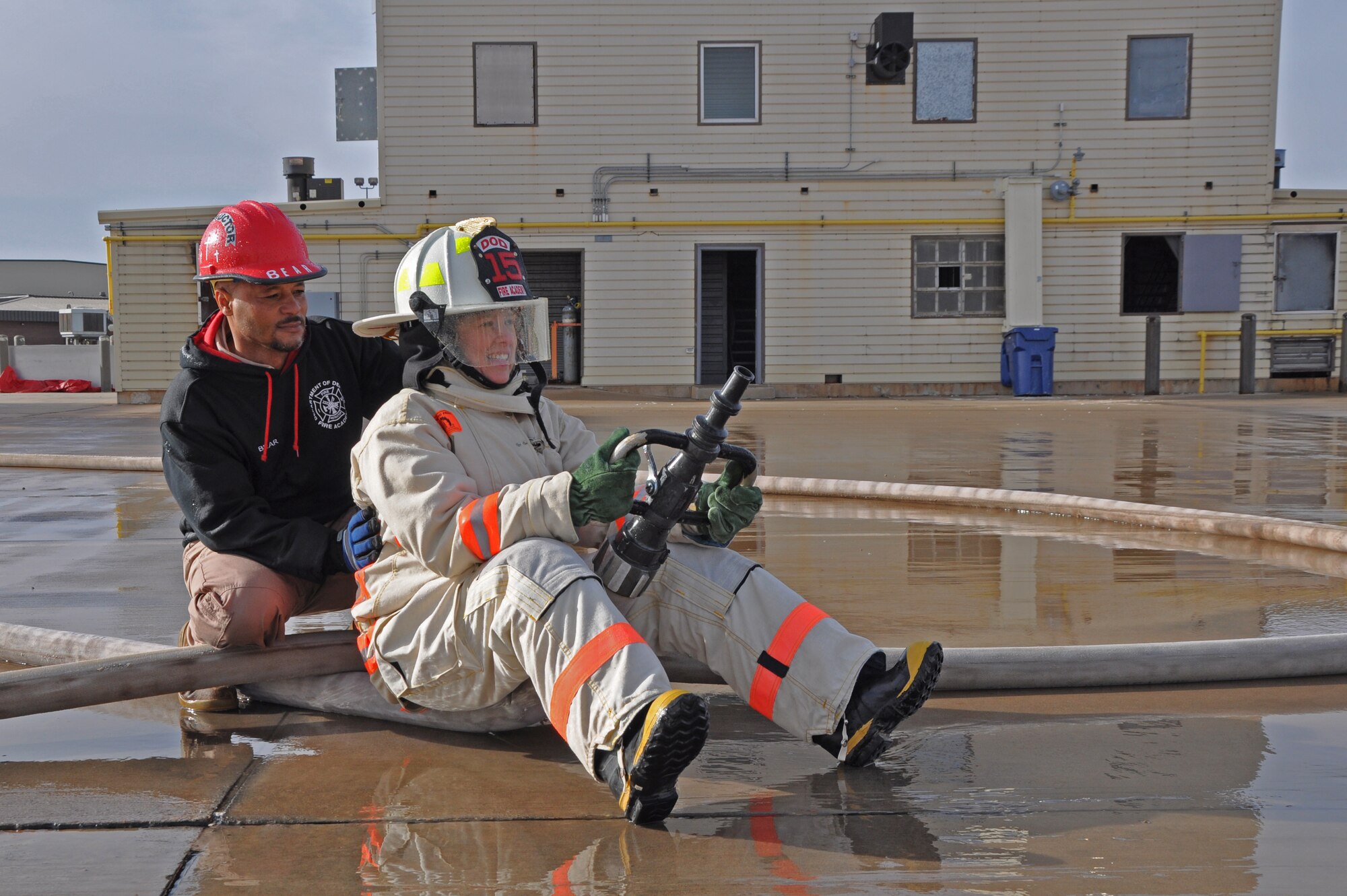 GOODFELLOW AIR FORCE BASE, Texas – Danny Q. Hebert, 312th Training Squadron Block IV instructor, left, helps Col. Kimberlee P. Joos, 17th Training Wing Commander, right, use a water hose during the Fire Marshal Course at the Louis F. Garland DOD Fire Academy here March 19. The fire academy hosts a minimum of 15 advanced fire protection courses. (U.S. Air Force photo/ Airman 1st Class Breonna Veal)