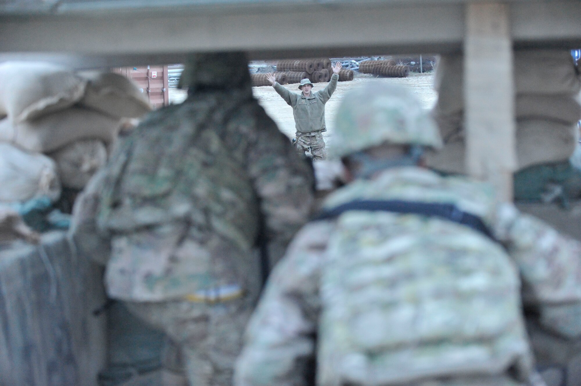Two members of the 455th Expeditionary Maintenance Squadron watch another member playing the role of a suspicious person during an exercise at Bagram Airfield, Afghanistan, March 13, 2014. Service members are trained to stop any unauthorized or suspicious personnel attempting to enter their area.(U.S. Air Force photo by Senior Master Sgt. Gary J. Rihn/Released)