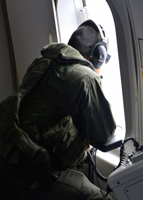 U.S. Navy Petty Officer 1st Class Robert Pillars looks for floating debris while aboard a P-8A Poseidon at sea, March 24, 2014, during a mission to assist in the search for Malaysia Airlines Flight 370. Pillars is an aircrewman assigned to Patrol Squadron 16.