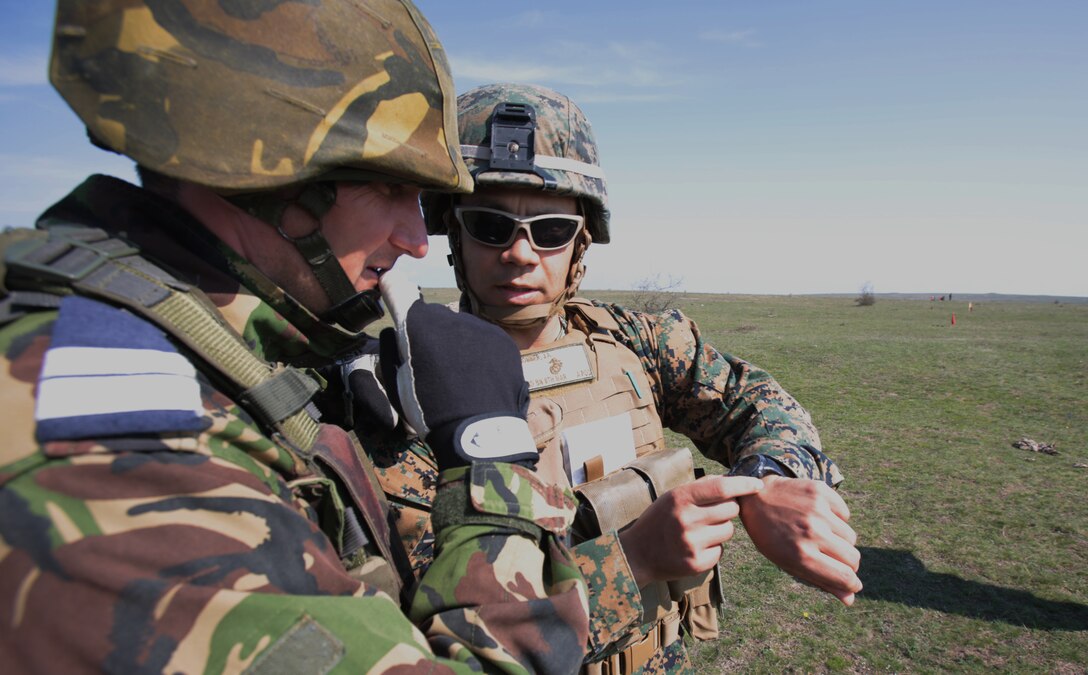 Sergeant John Sommer, mortarman, Weapons Company, 3rd Battalion, 8th Marines, assigned to Black Sea Rotational Force 14 shows the features of his watch to a Romanian service member assigned to the Romanian 307th Naval Infantry,  during a combined maneuver live fire exercise at Babadag Training Area, Romania, 26 March, 2014.  Romanian service members and Marines from BSRF-14 integrated fire teams during the live fire exercise.  Black Sea Rotational Force 14 is a task force of Marines and sailors with the mission to sustain positive relationships with partner nations uphold regional stability and increase military operational capabilities while also proving the ability for rapid crisis response in the Black Sea, Balkan and Caucasus regions of Eastern Europe. (Official Marine Corps photo by Staff Sgt. Tanner M. Iskra, BSRF Combat Camera/Released)