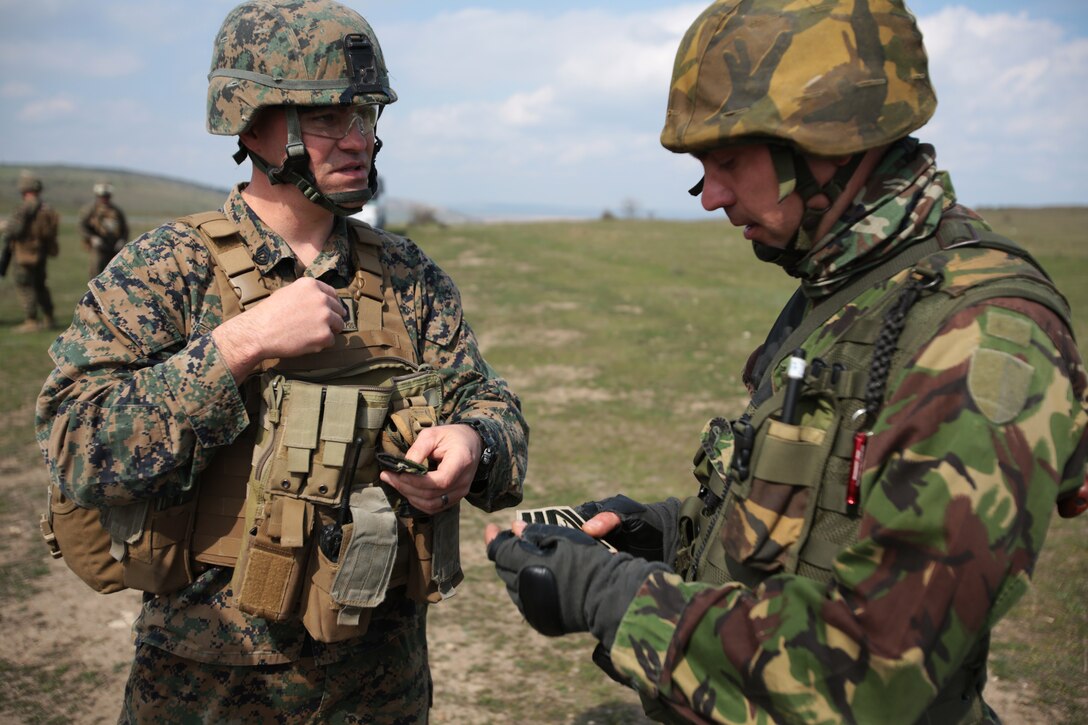 Gunnery Sergeant Matthew Richey, artilleryman, Weapons Company, 3rd Battalion, 8th Marines, assigned to Black Sea Rotational Force 14 exchanges rank insignias with a Romanian service member who has an equivalent rank during a combined maneuver live fire exercise at Babadag Training Area, Romania, 26 March, 2014.  During exercises, exchanging gifts among service members from different countries signifies comradeship. Black Sea Rotational Force 14 is a task force of Marines and sailors with the mission to sustain positive relationships with partner nations uphold regional stability and increase military operational capabilities while also proving the ability for rapid crisis response in the Black Sea, Balkan and Caucasus regions of Eastern Europe. (Official Marine Corps photo by Staff Sgt. Tanner M. Iskra, BSRF Combat Camera/Released)