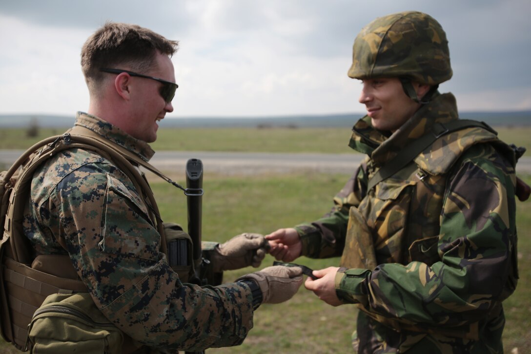 Lance James Costa, mortarman, weapons company, 3rd Battalion, 8th Marines, assigned to Black Sea Rotational Force 14 exchanges a gift with a Romanian service member during a combined maneuver live fire exercise at Babadag Training Area, Romania, 26 March, 2014.  During exercises, exchanging gifts among service members from different countries signifies comradeship. Black Sea Rotational Force 14 is a task force of Marines and sailors with the mission to sustain positive relationships with partner nations uphold regional stability and increase military operational capabilities while also proving the ability for rapid crisis response in the Black Sea, Balkan and Caucasus regions of Eastern Europe. (Official Marine Corps photo by Staff Sgt. Tanner M. Iskra, BSRF Combat Camera/Released)