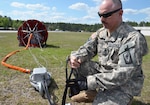 A member of the Rhode Island National Guard examines the connections to a collapsible firefighting bucket during aerial firefighting training with the Florida Army National Guard at Cecil Commerce Center in Jacksonville, Fla., March 20, 2014. 