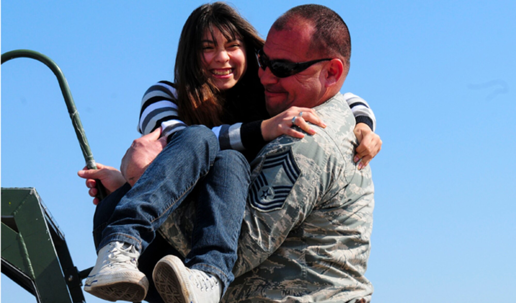 Chief Master Sgt. Caesar Acosta carries a wheelchair-bound Chilean girl up stairs to look inside the cockpit of an F-16 Fighting Falcon March 26, 2014, at the FIDAE Air Show in Santiago, Chile.  Nearly 60 Airmen are participating in subject matter expert exchanges with Chilean air force counterparts during FIDAE, and as part of the events are hosting static displays of the C-130 Hercules and F-16. Acosta is an aircraft maintenance specialist with the Texas Air National Guard. (U.S. Air Force photo/Senior Master Sgt. Miguel Arellano)