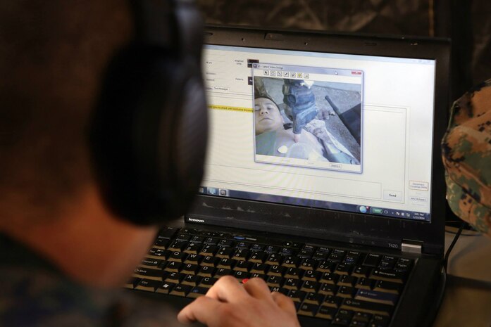 The medical officer on duty at the Battalion Aid Station watches the video feed of a simulated injury during a Marine Corps Warfighting Laboratory limited technical assessment. The Tempus Pro, portable vital signs monitor being used at the point of injury is able to transmit video, pictures, and vital signs to the next level of care while also enabling the medical providers to communicate through both voice and text.