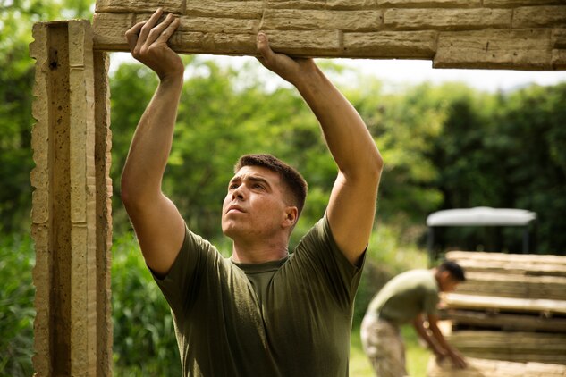 Lance Cpl. Shawn Sullens, an engineer with Combat Logistics Battalion 3, slides part of a wall into position during a building project at Marine Corps Training Area Bellows, March 21, 2014. The project’s purpose is to modify shipping container units into a low quality home with a full roof, door and windows, to give the simulated appearance of a real home within the training area. The units placed in remote areas between military operations on urban terrain facilities would provide Marines a better training experience when patrolling through the different sites. (U.S. Marine Corps photo by Lance Cpl. Matthew Bragg)