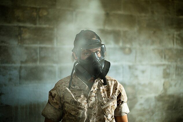 Lance Cpl. Alexandra Gehly, a signals intelligence specialist assigned to S-3 training with 3rd Radio Battalion, looks through the haze of CS gas after breaking the capsules during 3rd Radio Bn.’s annual gas chamber training at Boondocker Training Area, March 25, 2014. (U.S. Marine Corps photo by Lance Cpl. Matthew Bragg)