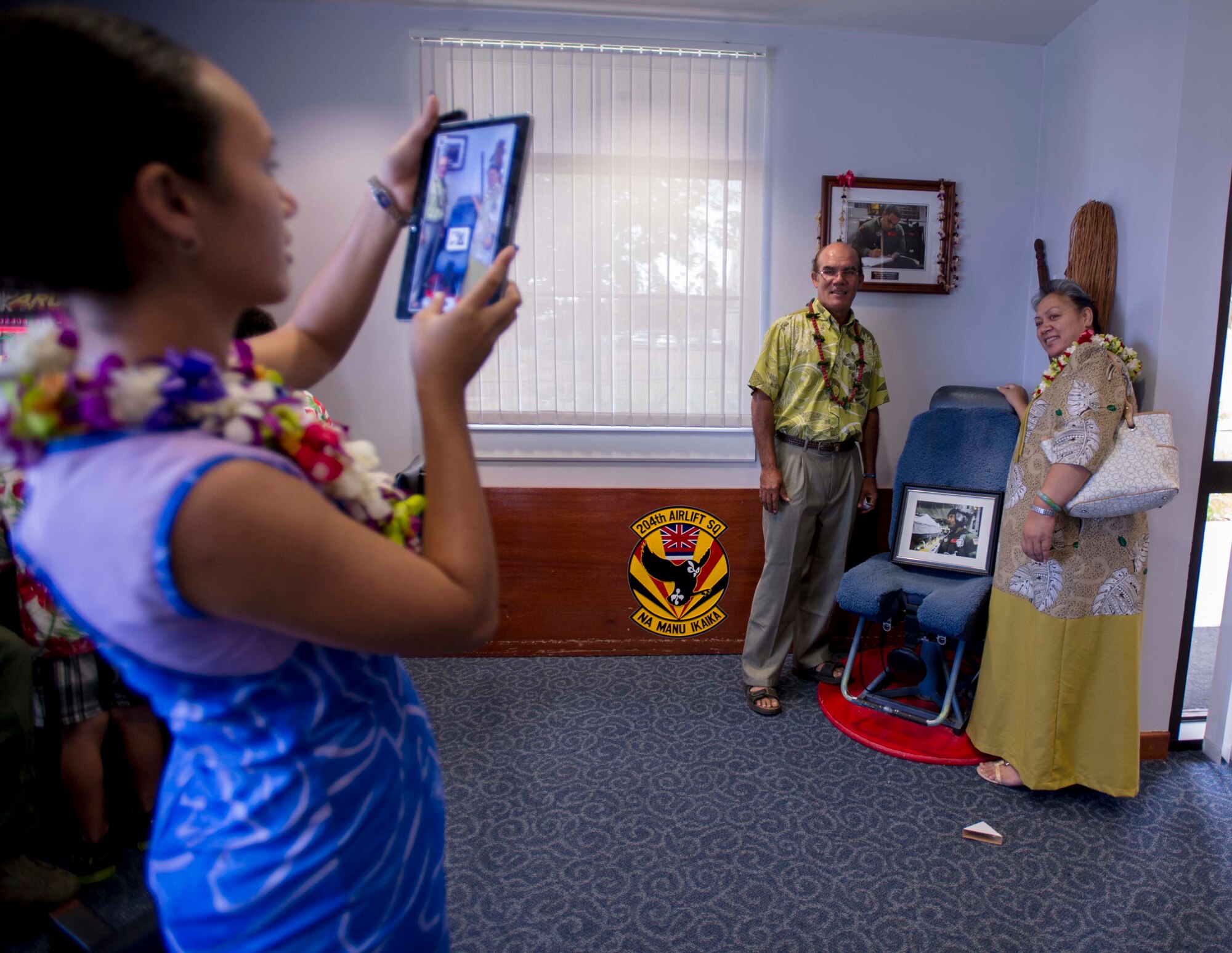 Toni-Marie Hollister snaps a photo of her parents, Tony Hollister, left, and Ann-Marie Hollister, right, standing near a memorial for Staff Sgt. Robert “Danny” Hollister on display in the 535th Heritage Room on Joint Base Pearl Harbor-Hickam, Hawaii, March 28, 2014. The family flew in from America Samoa to attend the 535th Auditorium rededication ceremony, which renamed the room the Hollister Auditorium, in memory of the late Airman. (U.S. Air Force photo/Tech. Sgt. Terri Paden)