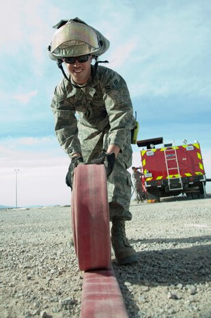 Airman 1st Class Cody Malia, 99th Civil Engineer Squadron firefighter, roles up a fire hose after a training certification exercise March 27, 2014 at Nellis AFB, Nev. Fire hoses are designed to quickly role out for use in case of an emergency. (U.S. Air Force photo by Airman 1st Class Timothy Young)