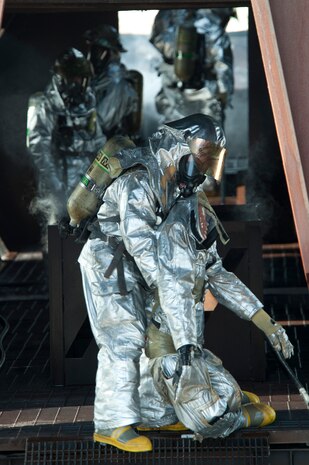 Firefighters from Nellis and Creech Air Force Bases, simulate rescuing a victim during an aircraft burn trainer during a training certification exercise March 27, 2014 at Nellis AFB, Nev. During the exercise firefighters are tasked with extinguishing a fire on the interior and exterior of the aircraft. (U.S. Air Force photo by Airman 1st Class Timothy Young)