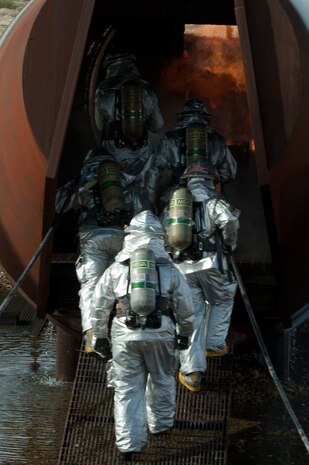 Firefighters from Nellis and Creech Air Force Bases, enter through the back of an aircraft burn trainer during a training certification exercise March 27, 2014 at Nellis AFB, Nev. During the exercise firefighters are tasked with extinguishing a fire on the interior and exterior of the aircraft. (U.S. Air Force photo by Airman 1st Class Timothy Young)