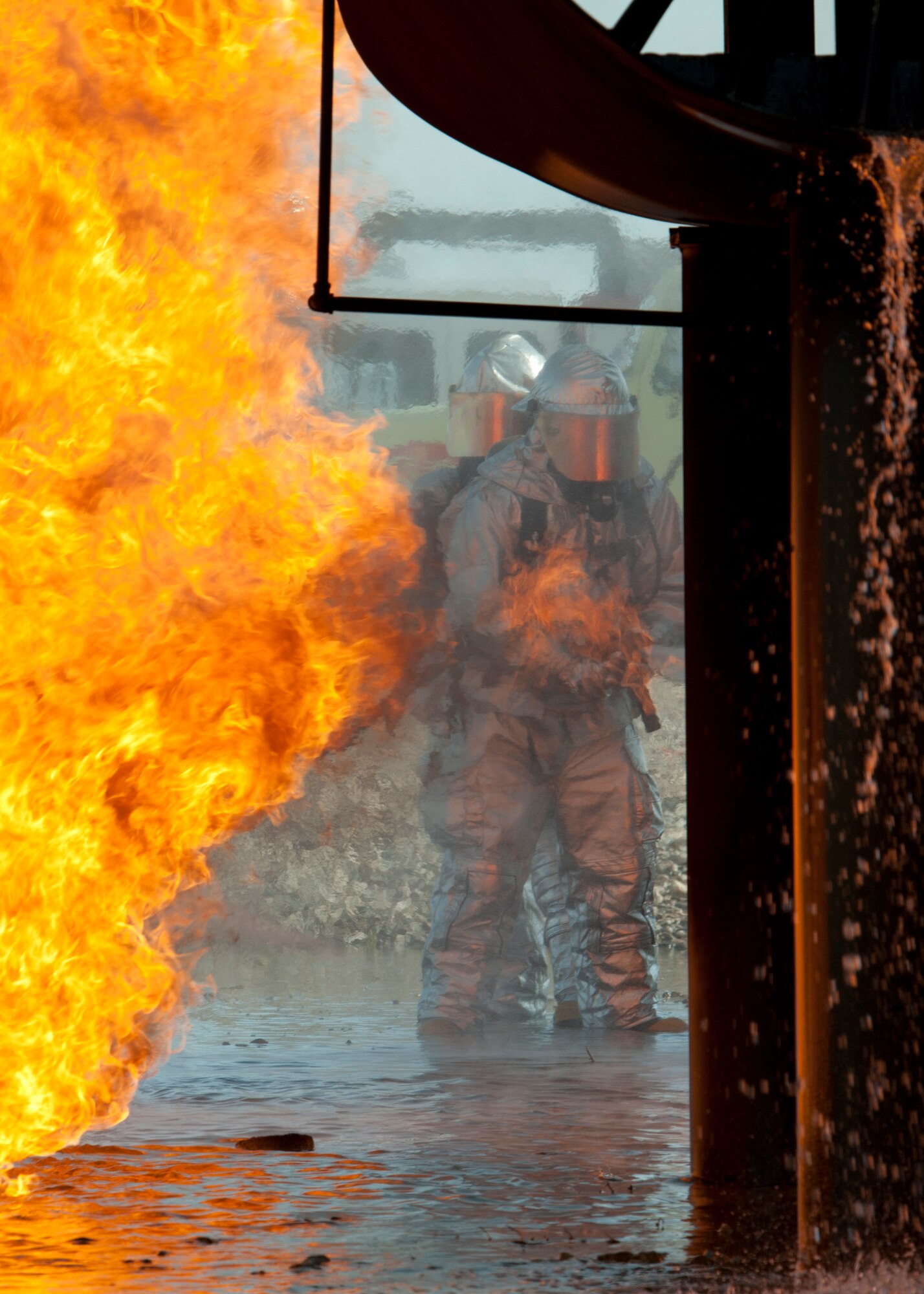 Firefighters from Nellis and Creech Air Force Bases, spray water on an aircraft burn trainer during a training certification exercise March 27, 2014 at Nellis AFB, Nev.   The rapid intervention vehicle can spray water at an ultra-high pressure and up to a rate of 1,500 gallons per minute. (U.S. Air Force photo by Airman 1st Class Timothy Young)