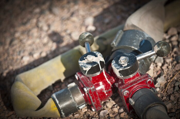 A three-way ball valve is connected to three fire hoses prior to an aircraft fire training certification exercise March 27, 2014 at Nellis Air Force Base, Nev. The three-way ball valve is adapted to quickly distribute water through hoses of different sizes depending on the emergency requirements. (U.S. Air Force photo by Airman 1st Class Joshua Kleinholz)