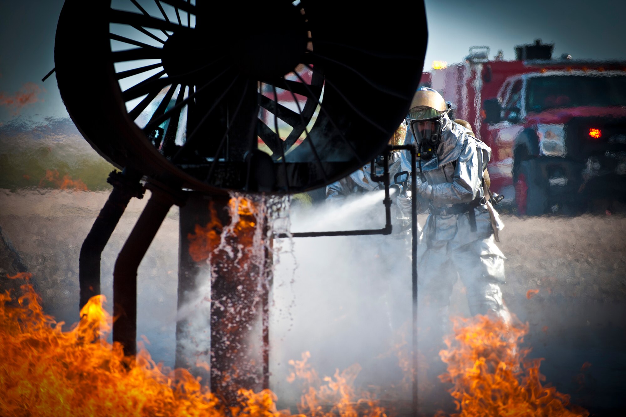 Airman First Class Cameron Fox, the 99th Civil Engineer Squadron firefighter, works with fellow Airmen to extinguish a simulated aircraft fire during a training certification exercise March 27, 2014 at Nellis Air Force Base, Nev. Air Force firefighters train to respond to a multitude of possible emergencies both on the flightline and within the base community. (U.S. Air Force photo by Airman 1st Class Joshua Kleinholz)