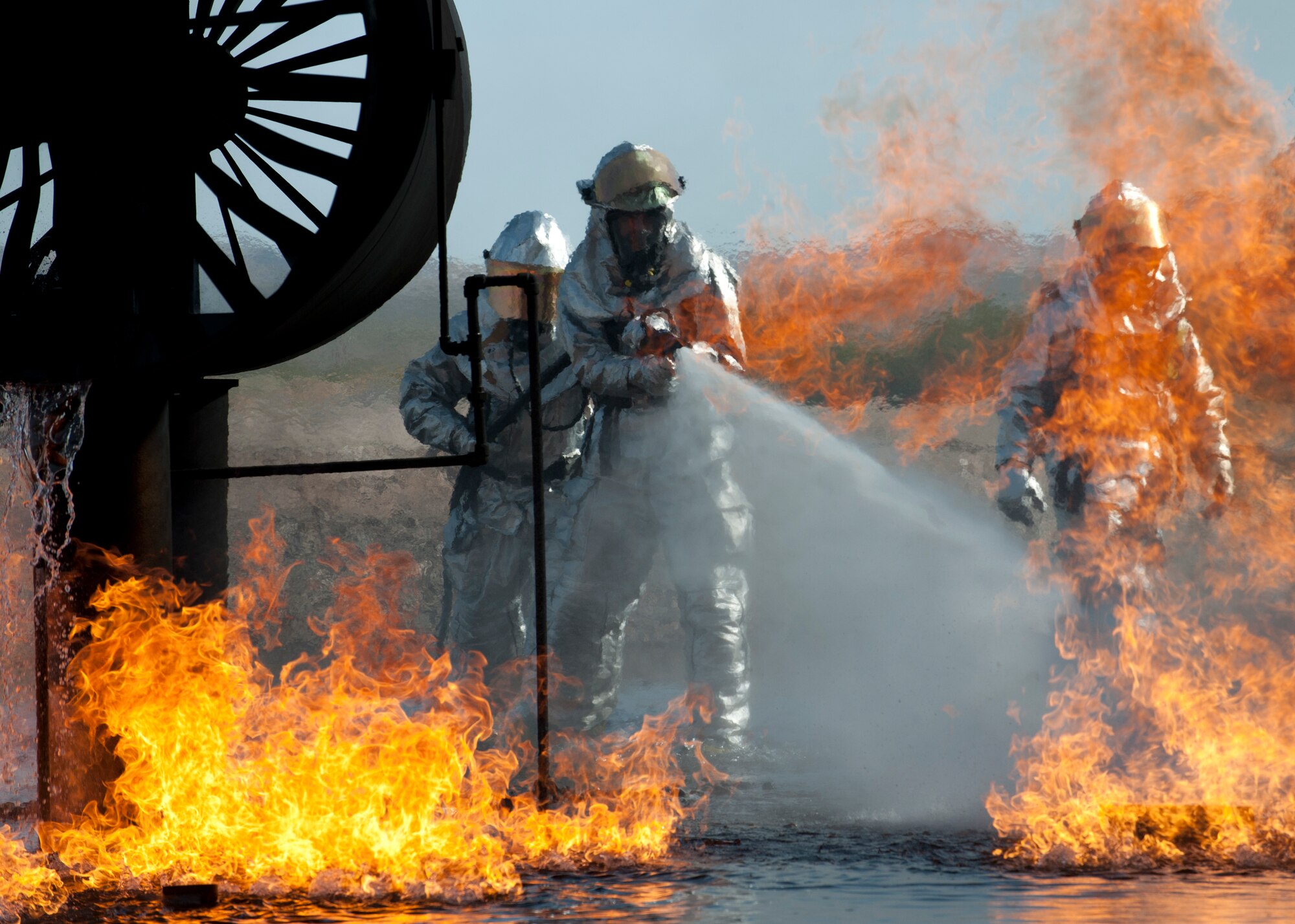 Firefighters with the 99th Civil Engineering Squadron subdue a fire during a training exercise at the aircraft burn trainer March 27, 2014, at Nellis Air Force Base, Nev. The firefighters train by putting out real fires on a mock aircraft. The training helps ensure smooth and efficient operations for potential real-world aircraft fires. (U.S. Air Force photo by Airman 1st Class Thomas Spangler) 